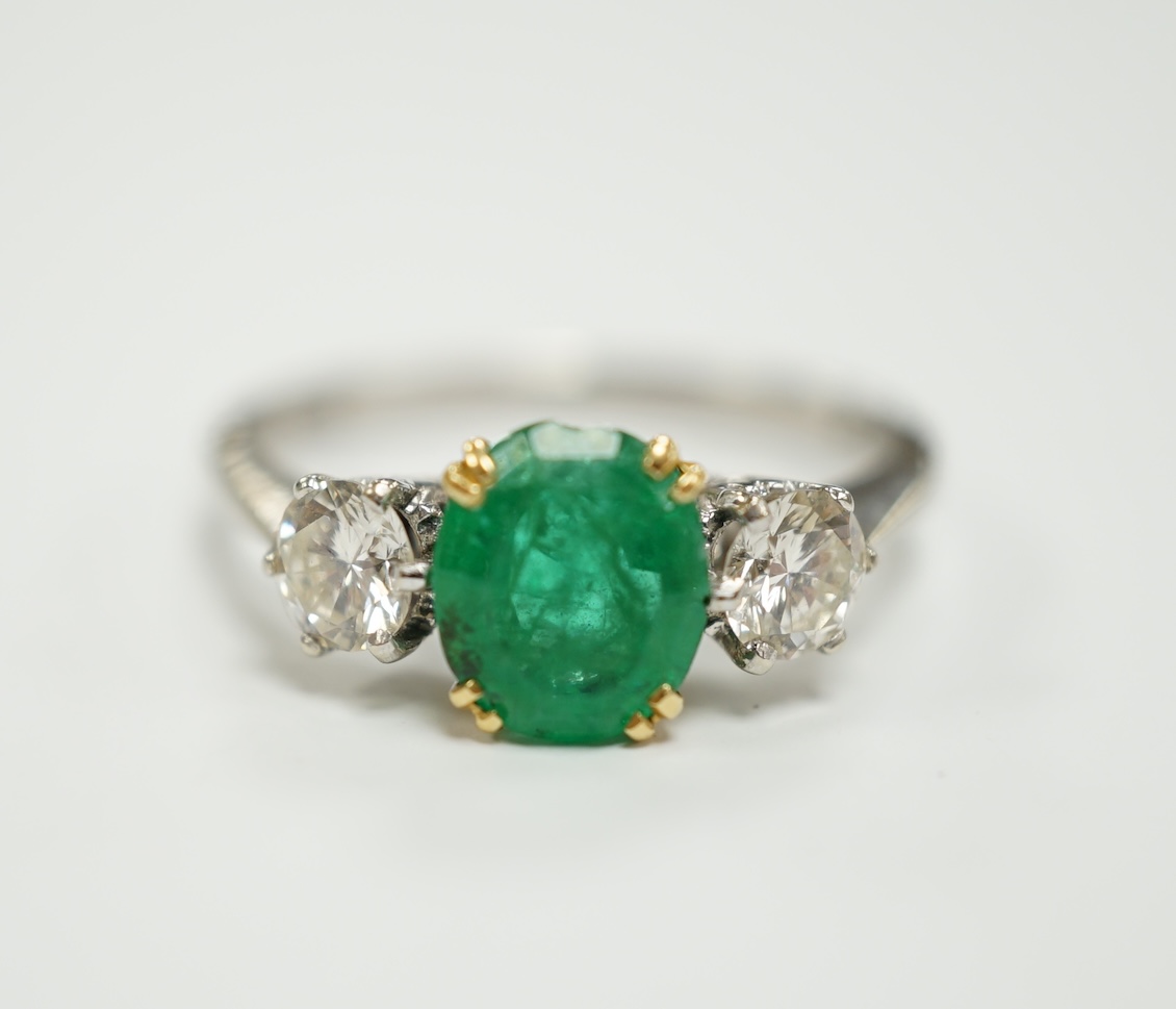 A 1970's 18ct white gold, single stone oval cut emerald and two stone diamond set ring, size P/Q, gross weight 3.2 grams.